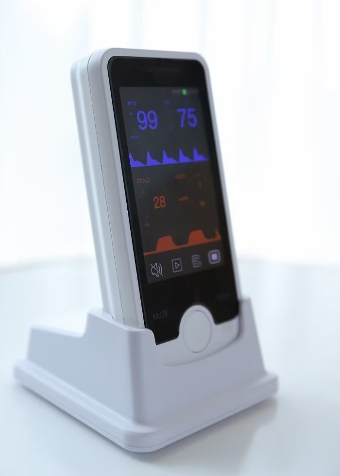 VE4 handheld monitor seated in the charging base, side profile showing the slim 29 mm body